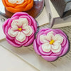 A pink silicone mold shaped like a rose flower with white petals and a yellow center.