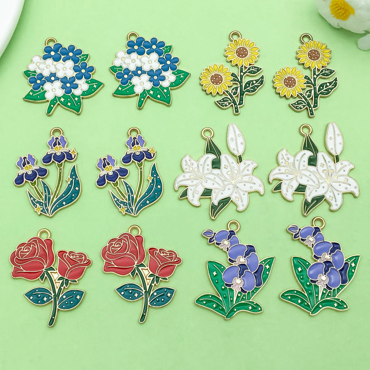 A collection of colorful enamel flower charms featuring blue, yellow, and red roses and blossoms for jewelry making.