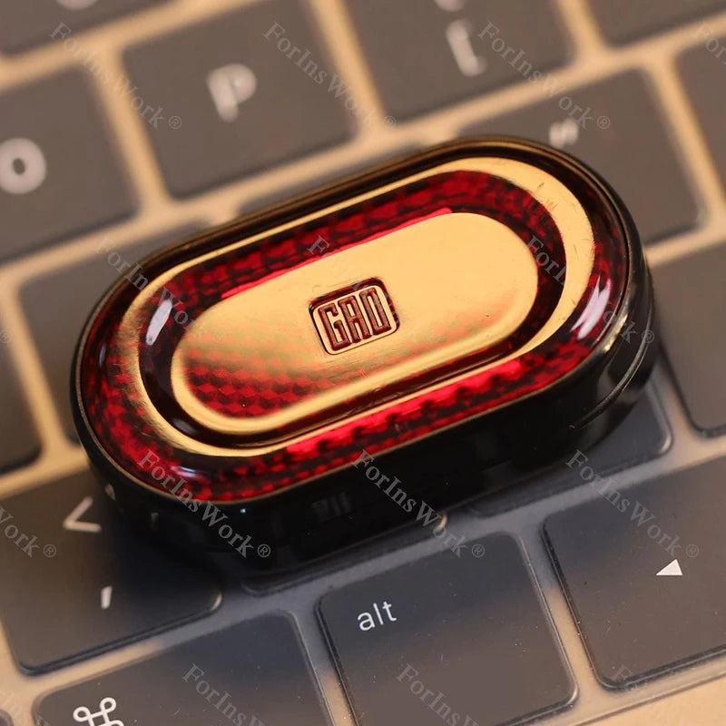A close-up of a gold and red metal mechanical fidget slider with a gem design resting on a keyboard.