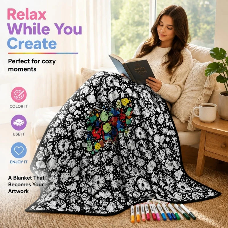 A black and white patterned blanket displayed on a sofa next to a cup of tea and art markers.
