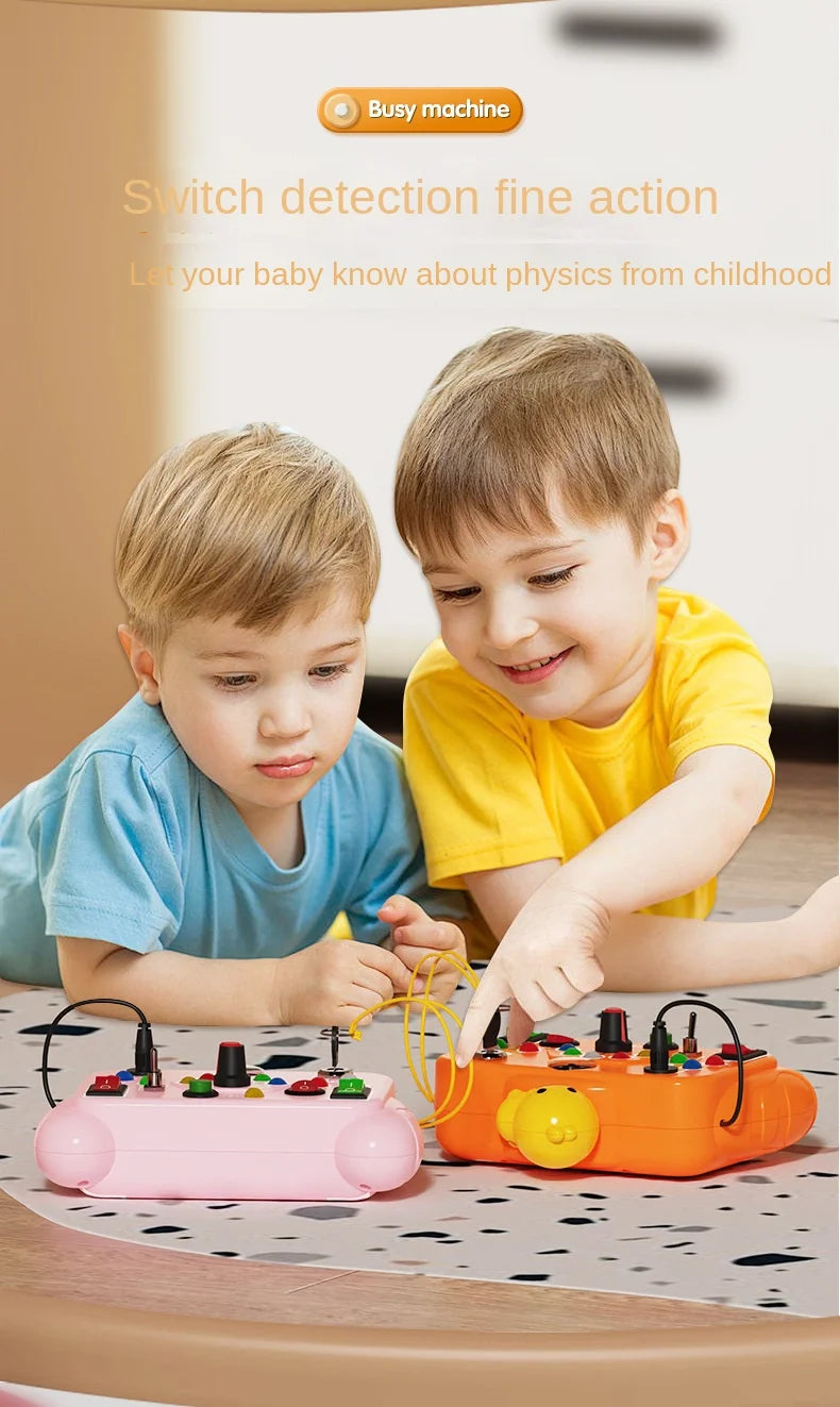 A toddler is interacting with a pink busy board featuring various switches and components for physics learning.