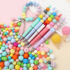 A colorful mix of round silicone beads in various shades of pink, blue, yellow, and green, alongside several paintbrushes.