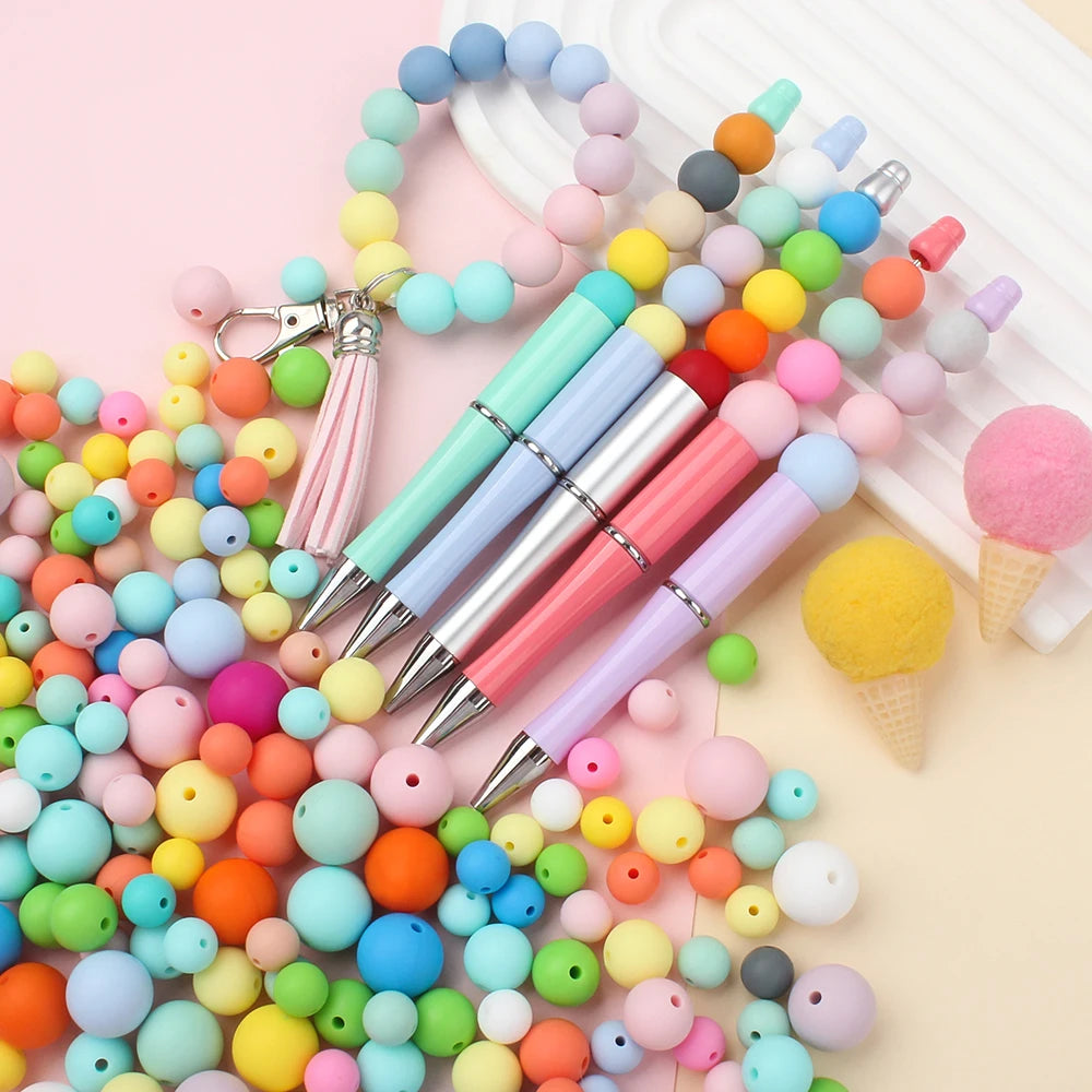 A colorful mix of round silicone beads in various shades of pink, blue, yellow, and green, alongside several paintbrushes.
