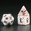 A set of acrylic dice, including a tetrahedral die and a cube, with red blood effect markings on a dark background.