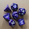 A collection of ten purple acrylic polyhedral dice scattered on a brown surface.
