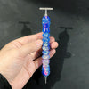 A hand holds a colorful diamond painting pen with a stainless steel tip, displaying iridescent blue and purple hues.