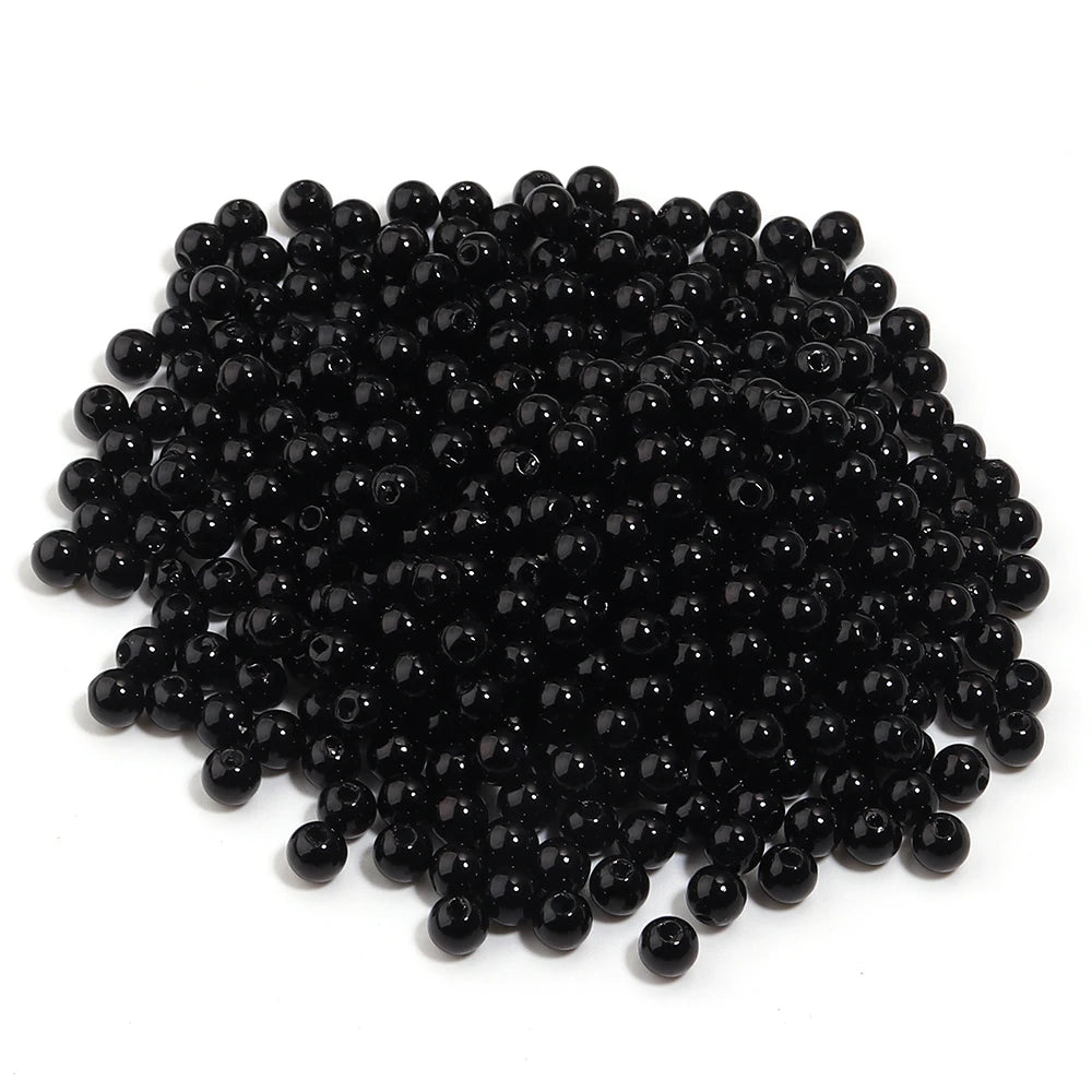 A pile of small, round, black imitation pearl beads for jewelry making.