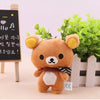 A fluffy brown Rilakkuma anime plush bear standing in front of a wooden sign with Korean text.