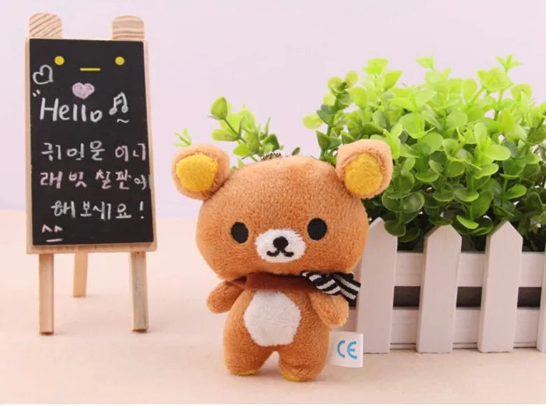 A fluffy brown Rilakkuma anime plush bear standing in front of a wooden sign with Korean text.