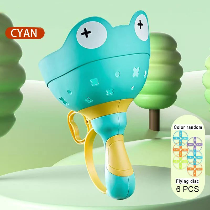 A cyan frog-shaped flying disc toy with a yellow handle is shown against a light green background.