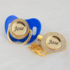 A gold-toned pacifier clip featuring the name Jose set against a bright blue background.
