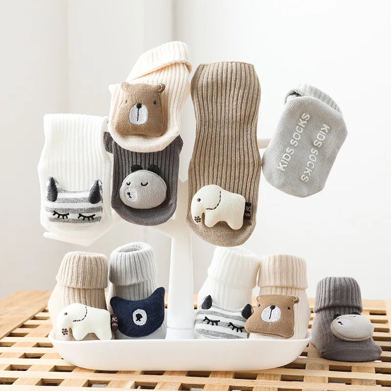 A collection of adorable cartoon non-slip cotton socks for babies and toddlers in various neutral colors.