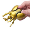 A hand holds a golden wind-up insect toy set featuring a ladybug, bee, and beetle.