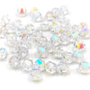 Clear faceted bicone crystal glass beads scattered on a white background for jewelry making