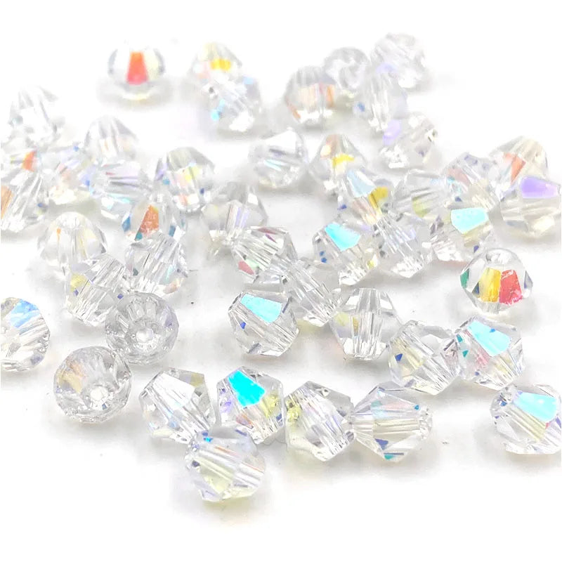 Clear faceted bicone crystal glass beads scattered on a white background for jewelry making