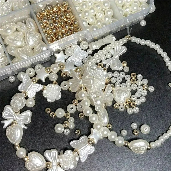 Colección de cuentas de perla blanca y dorada con formas de corazones, flores y mariposas.