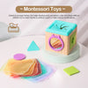 A wooden tissue box toy with colorful tissue paper and a green block, designed for developing fine motor skills.