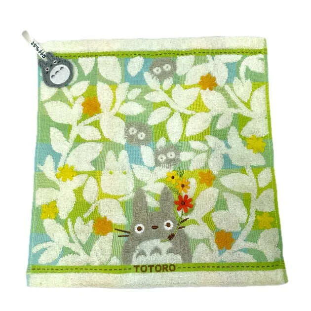 A soft stuffed animal featuring a cute gray cat design on a light green fabric.
