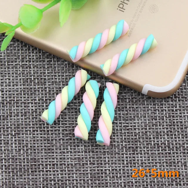 A collection of ten polymer clay marshmallow charms in pastel colors are displayed on a light-colored smartphone.