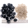 A collection of black and beige plastic safety eyes for amigurumi, shown next to a ruler.
