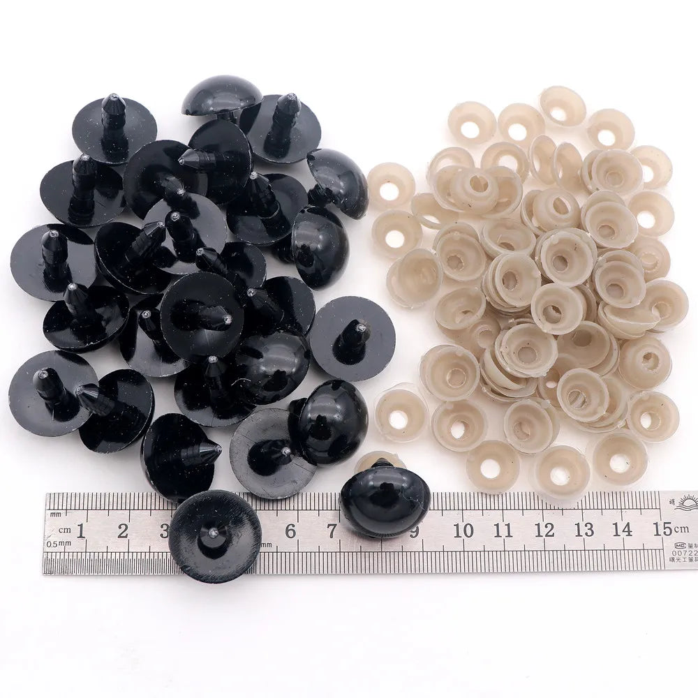 A collection of black and beige plastic safety eyes for amigurumi, shown next to a ruler.