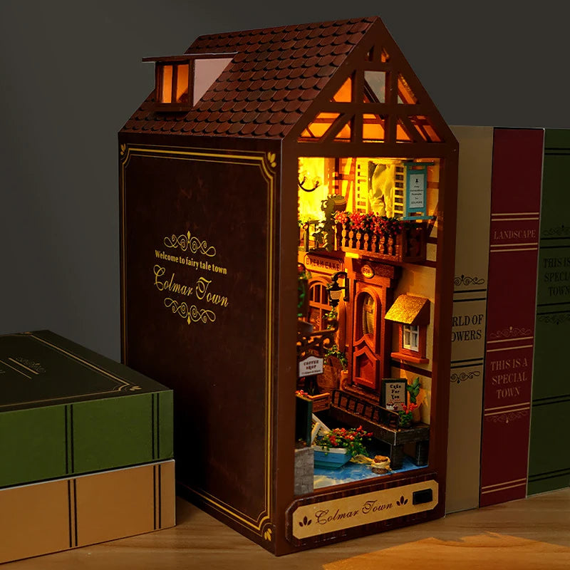 A wooden miniature house bookshelf book nook kit with internal LED lights and a tiled roof.