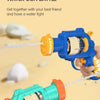 A hand holds a blue water gun and a teal water gun firing water at a sandy beach background.