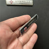 A silver aluminum alloy badge featuring the Umbrella Corporation emblem, held in a hand.