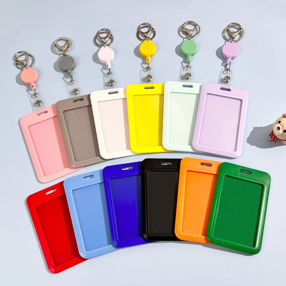 A collection of colorful retractable ID badge holders with keychain clips arranged in a row.
