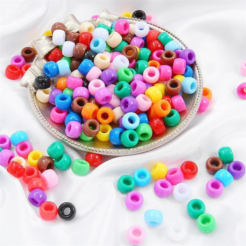 A pile of colorful pony beads in various shades of pink, blue, green, and orange scattered on a white surface.