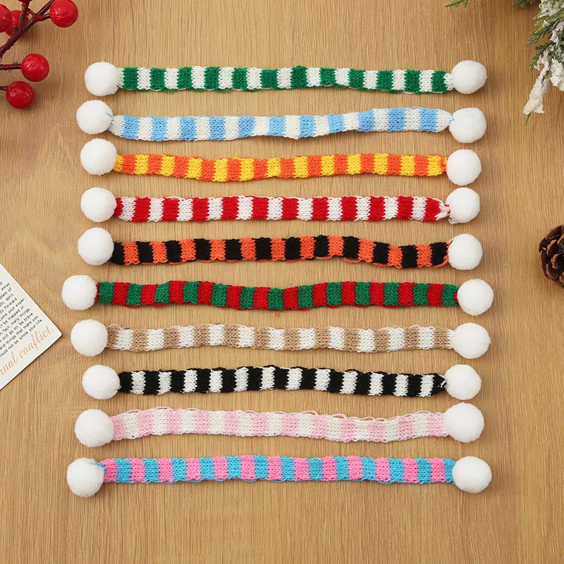 A set of mini knit Christmas hats and scarves featuring various striped colors like green, white, blue, red, and yellow.