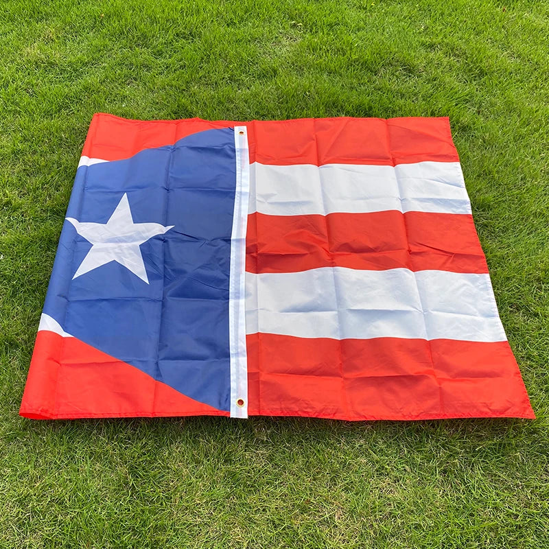 A large, folded Puerto Rico national flag made of red, white, and blue fabric lying on green grass.