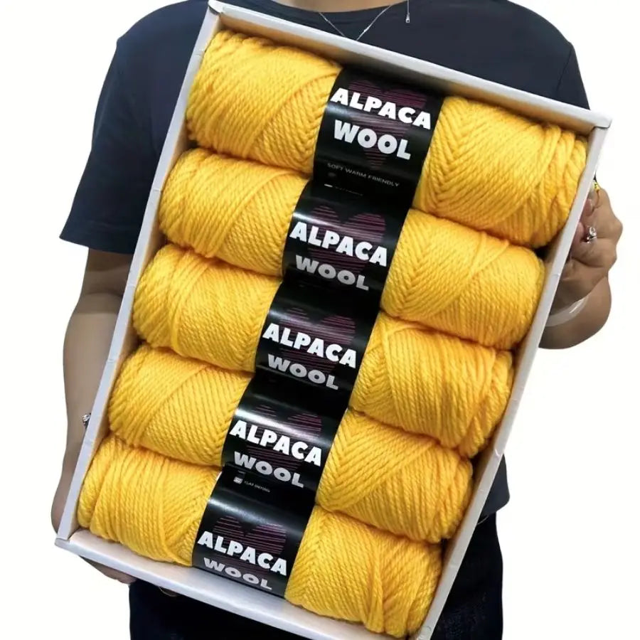 A box containing five skeins of yellow alpaca wool yarn for knitting and crochet projects.