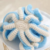 Adorable octopus plush toy with blue and white fuzzy tentacles resting on a white plate.