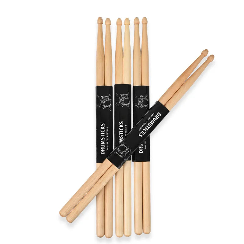 A set of premium maple drumsticks in natural wood and black packaging.