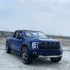 A blue 1:20 scale Ford Raptor F150 diecast model truck with lights parked on a gray outdoor surface.