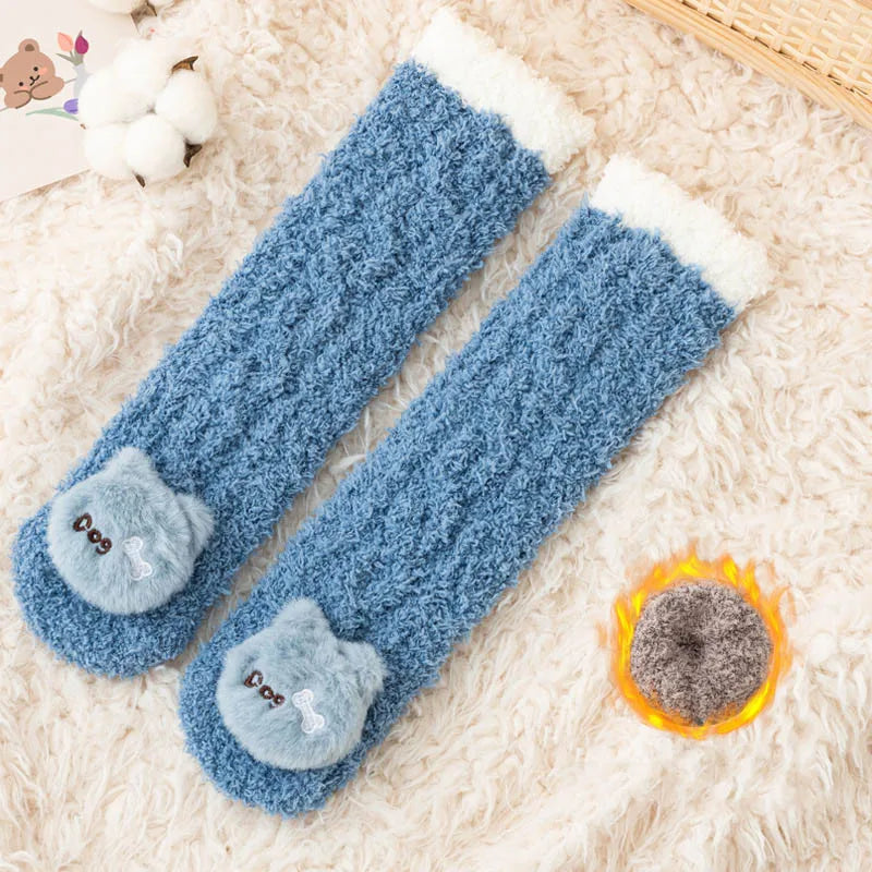 Pair of blue coral velvet baby knee-high socks with white fluffy trim resting on a cream sherpa fabric.