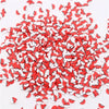 A pile of small red and white polymer clay flower charms for DIY crafts
