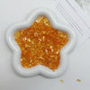 A white, five-pointed star shape filled with gold and orange acrylic ice strips for nail art and DIY crafts.