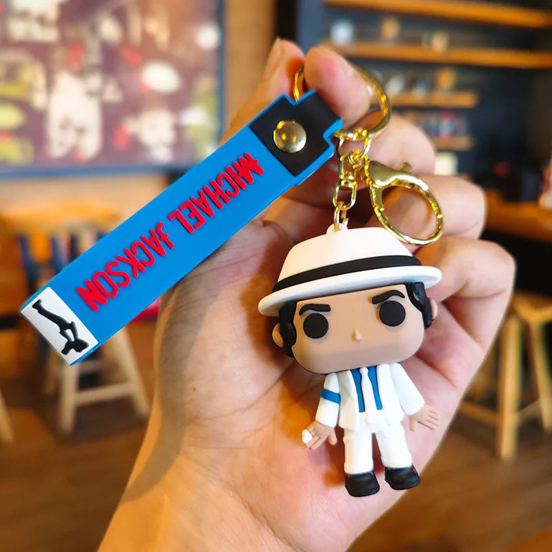 A keychain featuring a figure of Michael Jackson in a dance pose, attached to a blue tag.