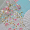 Pink and white nail art stickers featuring gold shells and starfish on a translucent background