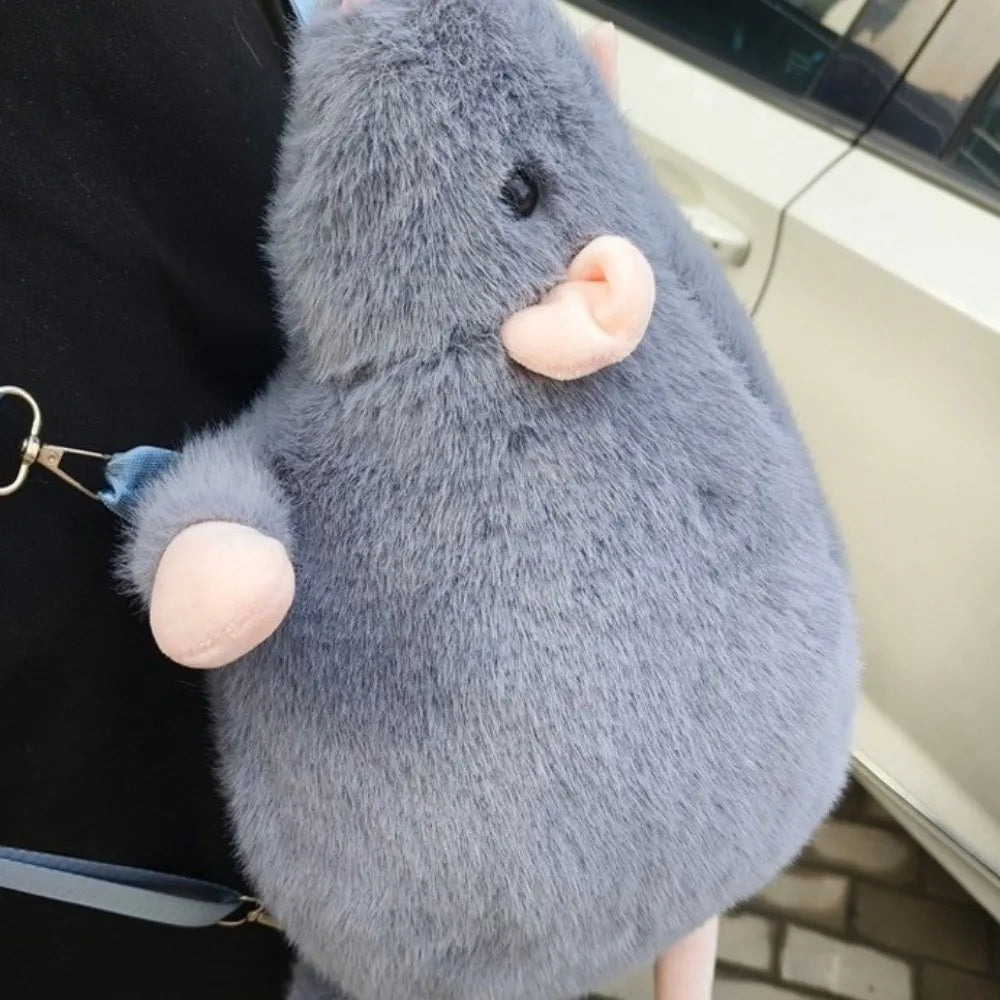 A soft gray mouse plush toy with pink ears is shown against a dark background.