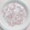 A collection of clear pink acrylic bow tie beads arranged on a white plate.