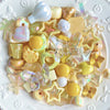 A collection of iridescent and translucent acrylic bow and flower beads in various pastel and golden tones for DIY jewelry ma