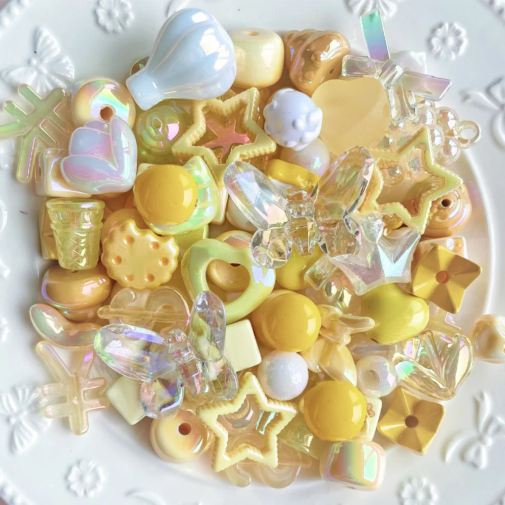 A collection of iridescent and translucent acrylic bow and flower beads in various pastel and golden tones for DIY jewelry ma