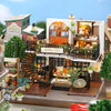 A detailed miniature dollhouse scene featuring a Momo Tea shop and surrounding architecture.