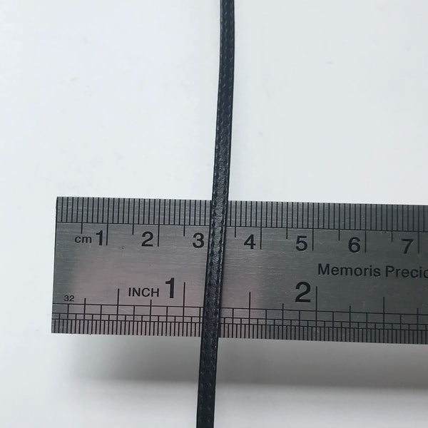 A close-up photo of a black cord or strap measured against a ruler marked in centimeters and inches.