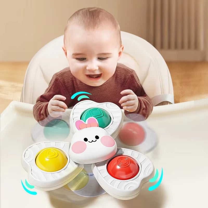 A baby is interacting with a spinning bath toy set featuring colorful, round objects.