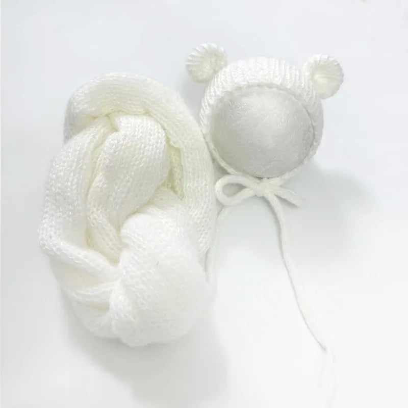 A white knit bear hat and wrap set with small ears and a pom-pom detail.