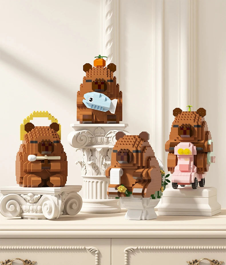 A set of cute capybara micro building blocks in brown and pink colors displayed on a light-colored cabinet.